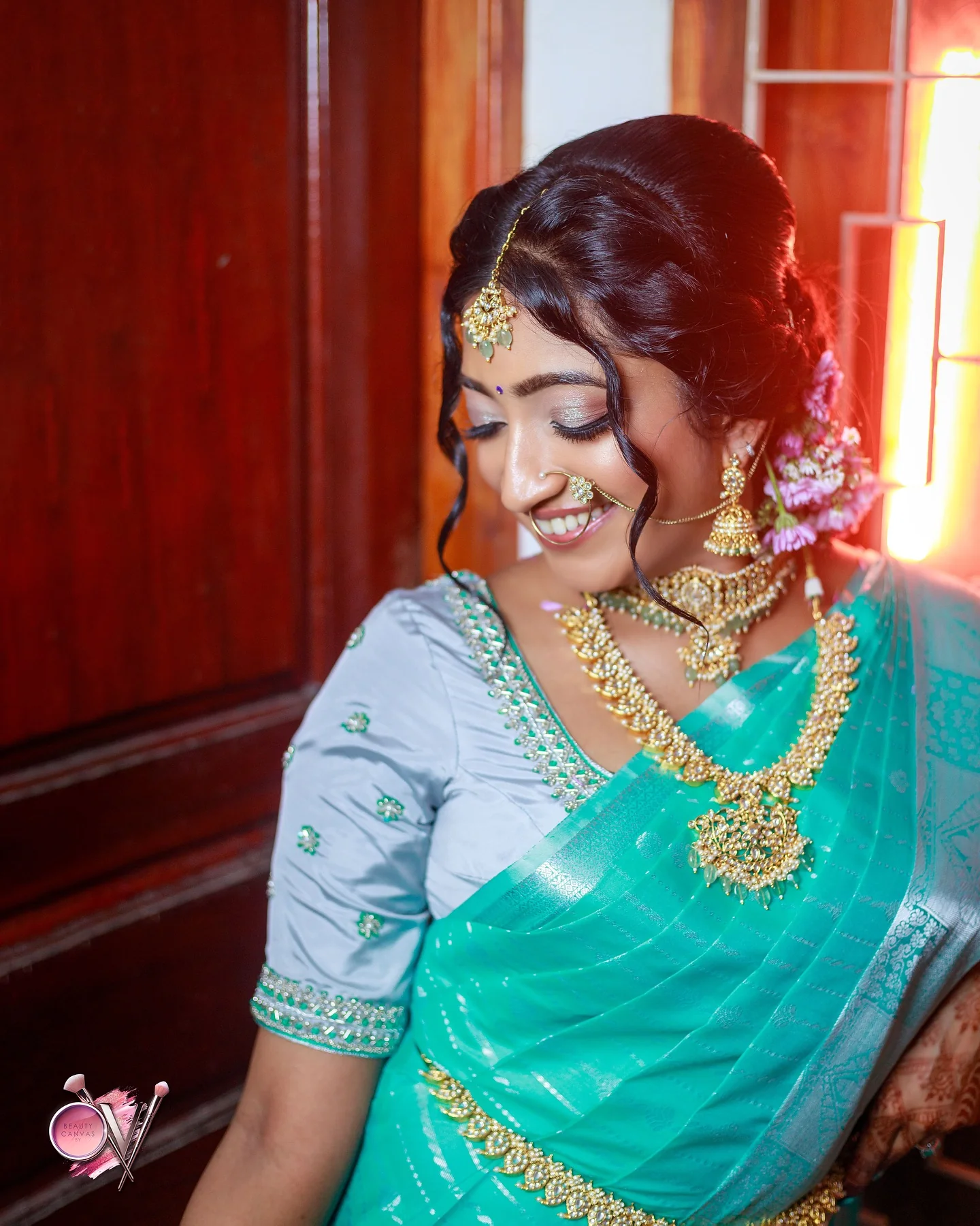 Makeup and gold temple jewellery in warm window light.