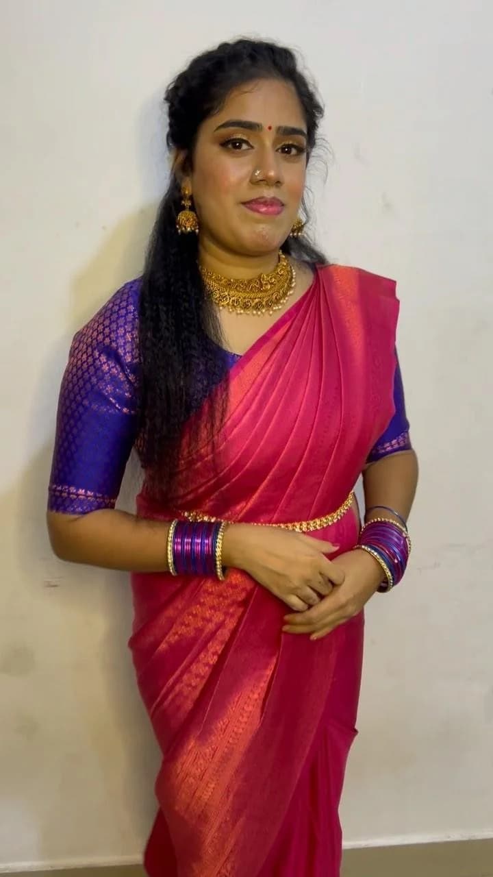 Occasion look in a pink silk saree with a blue blouse and gold jewellery.