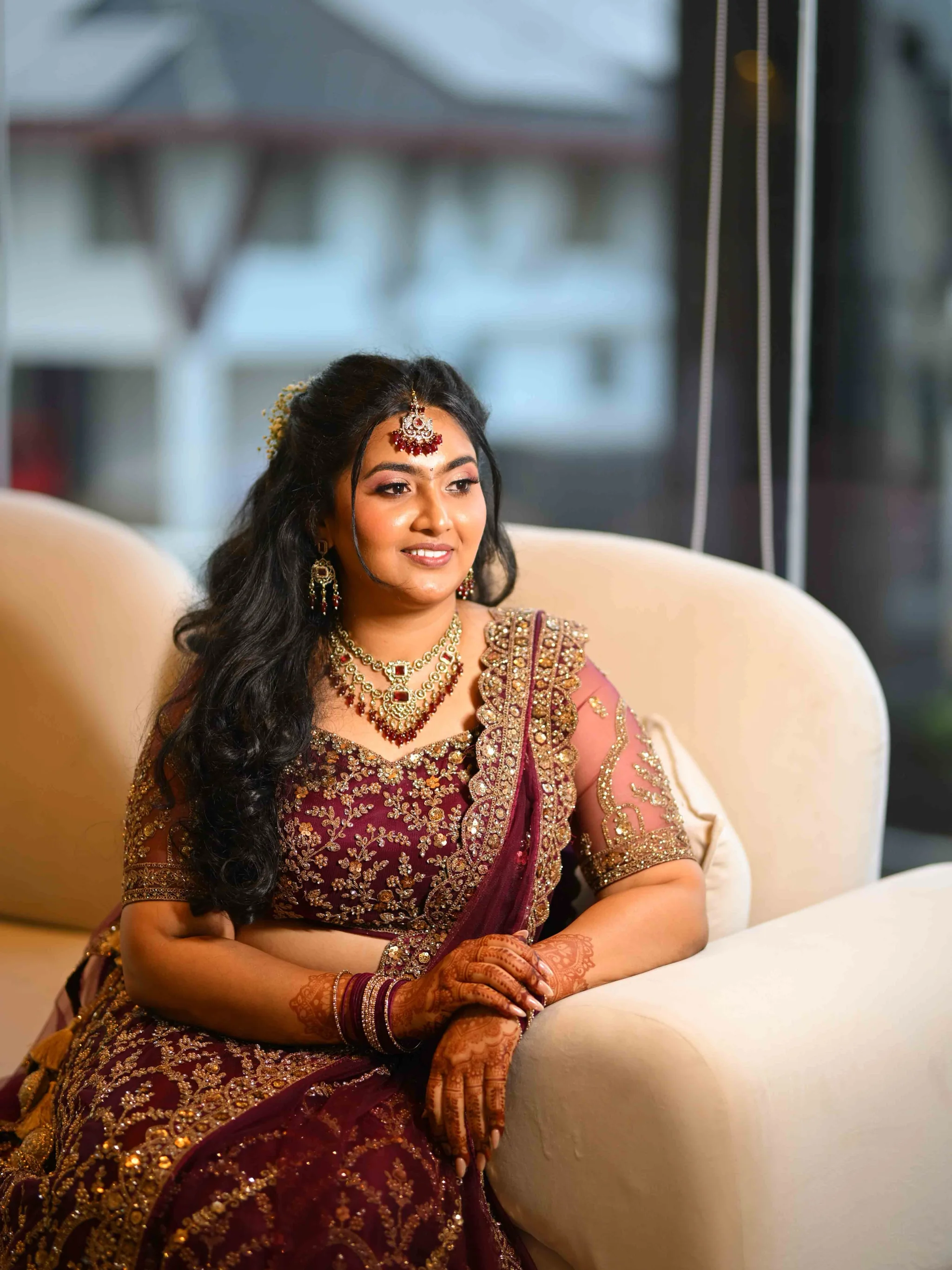 Seated bridal look with layered gold jewellery and softly waved hair.