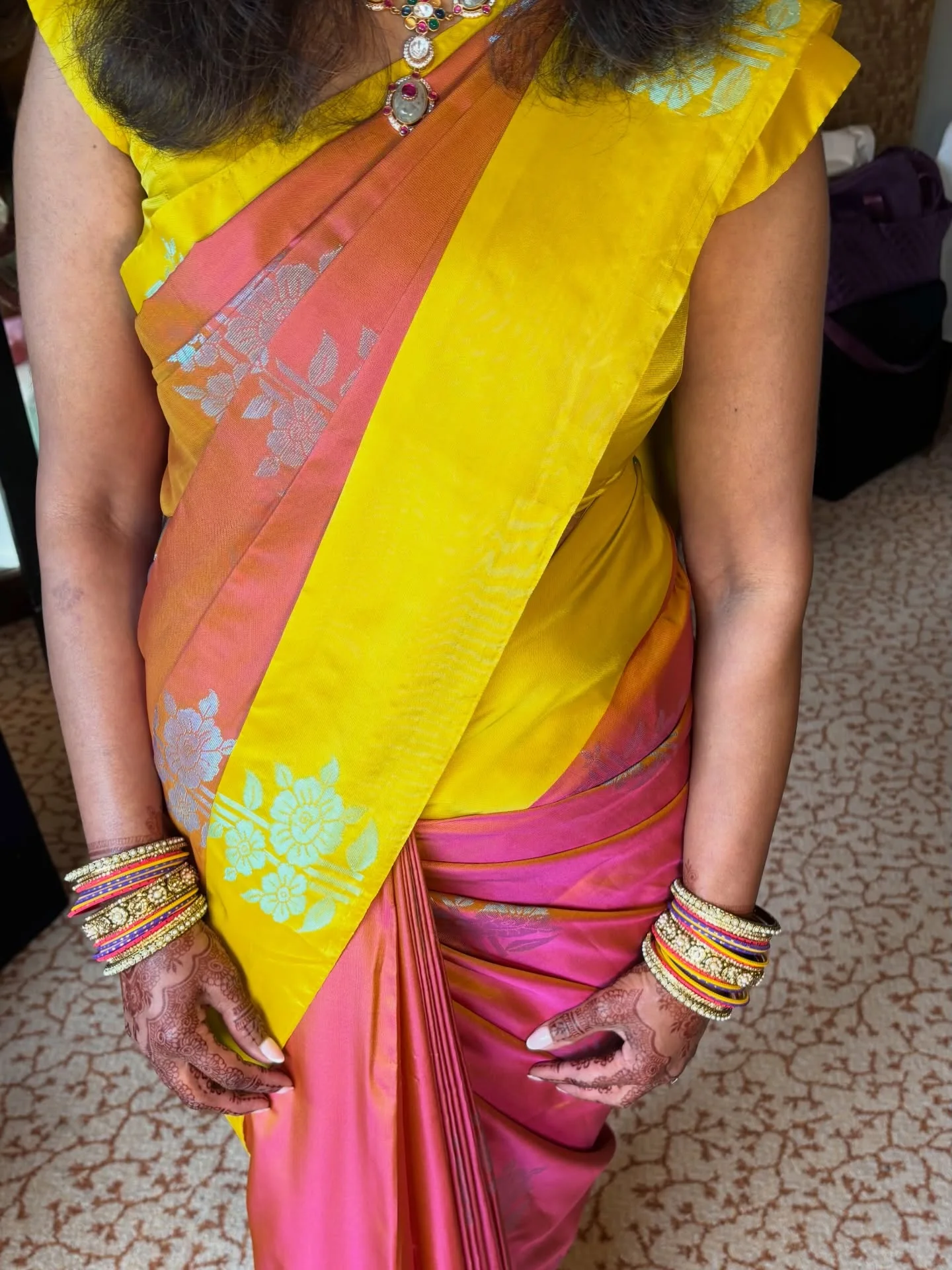Yellow and pink silk saree drape with the pleats held at the waist.